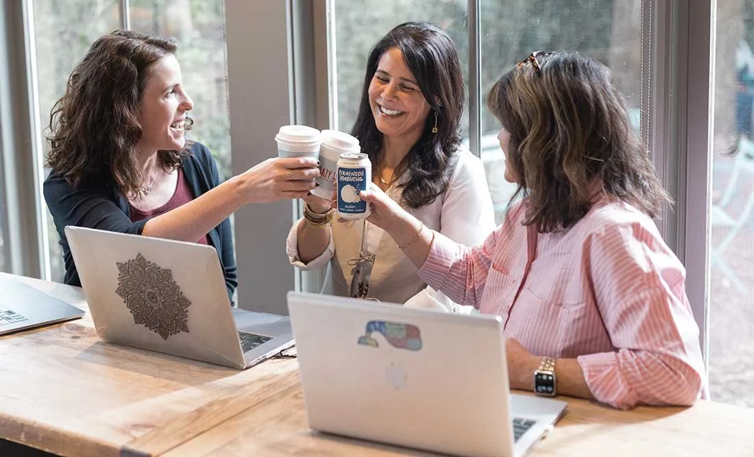 Melissa DeMayo working with clients at a table with laptops